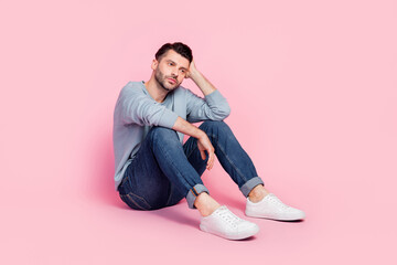 Obraz na płótnie Canvas Full body photo of nice young guy sitting depressed dreaming bored thoughtful dressed trendy blue clothes isolated on pink color background