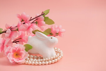 Old ceramic rabbit and cherry blossom on pink background.