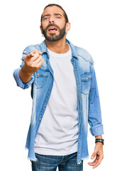Attractive man with long hair and beard wearing casual denim jacket pointing displeased and frustrated to the camera, angry and furious with you