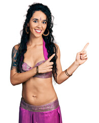 Young indian woman wearing belly dancer costume smiling and looking at the camera pointing with two...