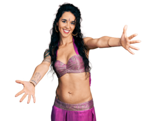 Young indian woman wearing belly dancer costume looking at the camera smiling with open arms for hug. cheerful expression embracing happiness.