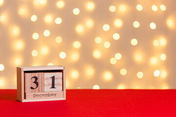 wooden calendar 31 december on red background and lights background