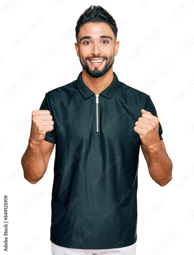 Sticker Young man with beard wearing sportswear celebrating surprised and amazed for success with arms raised and open eyes. winner concept.