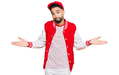Young man with beard wearing baseball uniform clueless and confused expression with arms and hands...