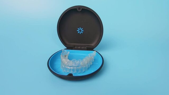 Invisalign braces or invisible transparent aligner on blue background front view
