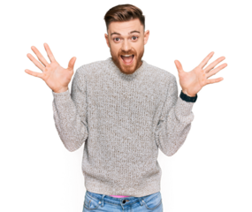 Young redhead man wearing casual winter sweater celebrating crazy and amazed for success with arms raised and open eyes screaming excited. winner concept