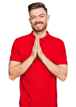 Young redhead man wearing casual clothes praying with hands together asking for forgiveness smiling confident.