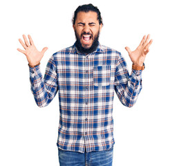 Naklejka premium Young arab man wearing casual clothes celebrating mad and crazy for success with arms raised and closed eyes screaming excited. winner concept