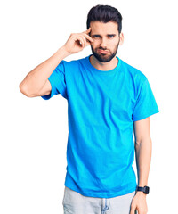 Young handsome man with beard wearing casual t-shirt worried and stressed about a problem with hand on forehead, nervous and anxious for crisis