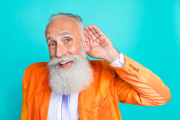 Portrait of funky positive man arm near ear listen empty space information isolated on turquoise...