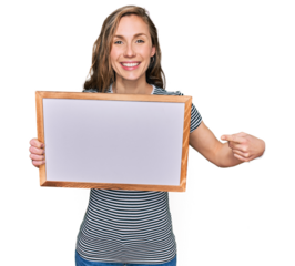 Young blonde woman holding empty white board smiling happy pointing with hand and finger