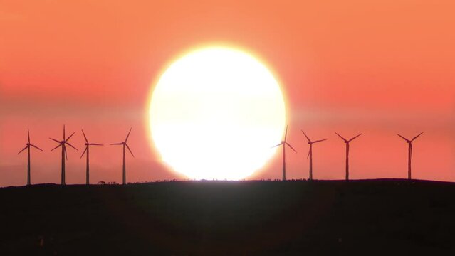 Sun rises behind windmill farm