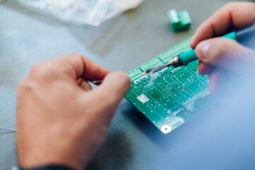 Electronics engineer hands working in a workshop with tin soldering parts