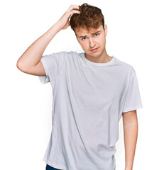 Young caucasian man wearing casual white t shirt confuse and wonder about question. uncertain with doubt, thinking with hand on head. pensive concept.