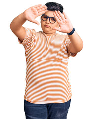 Little boy kid wearing casual clothes and glasses doing frame using hands palms and fingers, camera perspective