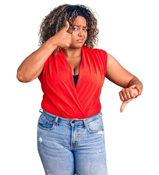Young african american plus size woman wearing casual style with sleeveless shirt doing thumbs up and down, disagreement and agreement expression. crazy conflict