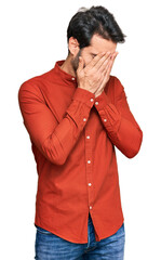 Young hispanic man wearing casual clothes with sad expression covering face with hands while crying. depression concept.