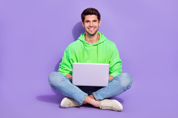 Full length photo of pretty positive man wear green hoodie chatting apple samsung modern gadget isolated purple color background