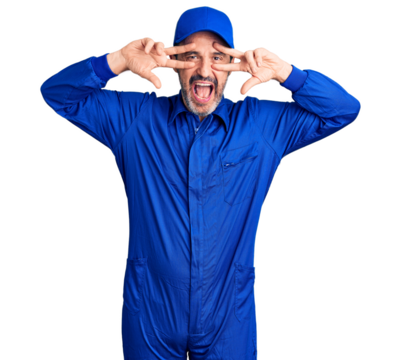 Middle age handsome man wearing mechanic uniform doing peace symbol with fingers over face, smiling cheerful showing victory