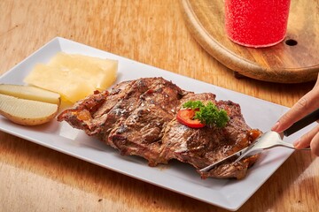 Closeup of high heat charcoal grilled steak served with cheese and pear on a white rectangular plate