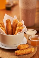 Vertical shot of fried mozzarella cheese sticks served in a white little bowl