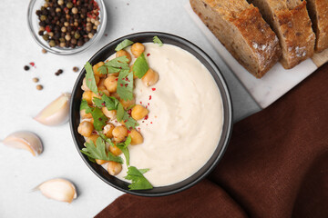 Flat lay composition of tasty chickpea soup in bowl, bread and spices served on light grey table