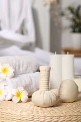 Fototapeta na wymiar Herbal bags, candles, rolled towels and beautiful flowers on wicker surface indoors. Spa products