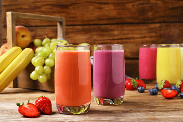 Glasses with different tasty smoothies and ingredients on wooden table