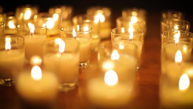 Camera moves past rows of glowing candles in a church or temple.