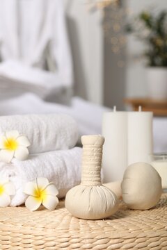 Herbal bags, candles, rolled towels and beautiful flowers on wicker surface indoors. Spa products