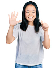 Young chinese woman wearing casual white t shirt showing and pointing up with fingers number six while smiling confident and happy.