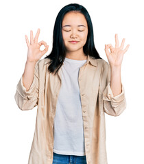 Young chinese woman wearing casual white t shirt and jacket relax and smiling with eyes closed doing meditation gesture with fingers. yoga concept.