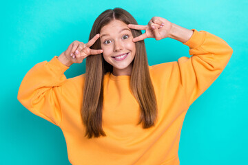 Fototapeta na wymiar Photo of youngster funny girl school learner take shot cover face v-sign wear orange sweater toothy smile isolated on aquamarine color background