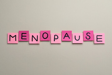 Pink paper notes with word Menopause on beige background, flat lay