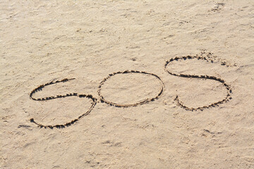 SOS message written on sandy beach outdoors