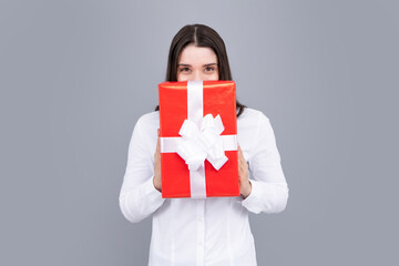 Fototapeta premium Happy birthday. Woman holding gift box with ribbon. Studio portrait over gray background.