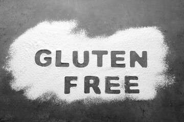 Fototapeta premium Words Gluten free written with flour on grey background, top view