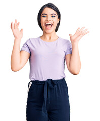 Brunette teenager girl wearing casual clothes celebrating crazy and amazed for success with arms raised and open eyes screaming excited. winner concept