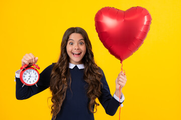 Obraz na płótnie Canvas Teen girl holding clock over yellow background. Early morning, daily schedule. Child checking time. do not be late. Punctual kid with alarm. Deadline time.