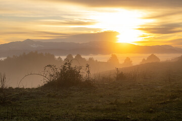 sunrise over a mountain below a misty valley

