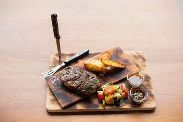 grilled meat steak and french fries on a wood plate.