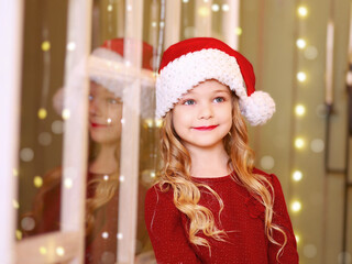 Little girl dreams of Christmas at the window