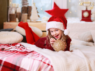 Little girl is holding glass ball in her hands. Toy for decorating Christmas tree. Happy childhood. 