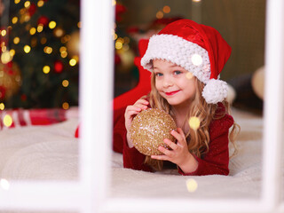 Little girl is holding glass ball in her hands. Toy for decorating Christmas tree. Happy childhood. 