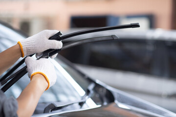 A mechanic wearing white gloves changes the wiper blades. change car wiper blades