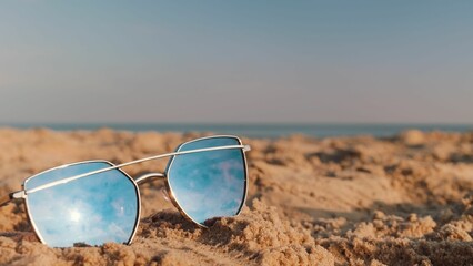 Closeup of sunglasses put on sand on the beach under the sunlight