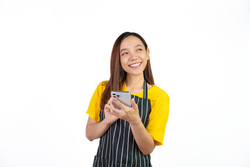 Texting on mobile to chat with customer, Portrait of confident asian woman barista and food owner shop with yellow t-shirt and black apron standing on white background.