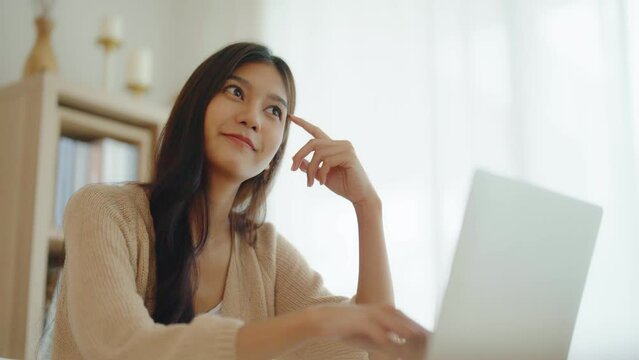 Young asian woman working on computer laptop on desk in living room at home