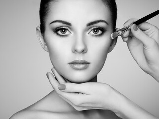Makeup artist applies skintone. Beautiful woman face. Perfect makeup. Skincare foundation. Black...
