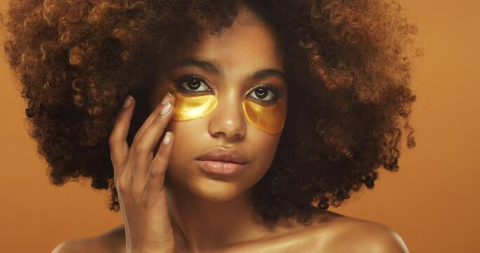 Beautiful african woman applying golden collagen eye patch with hand. Perfect clean fresh skin care treatment or cosmetic beauty